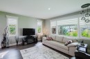 Spacious room featuring wood-finish flooring, multiple windows with blinds, and a modern ceiling light fixture - 14814 104 Avenue Nw, Edmonton, AB 