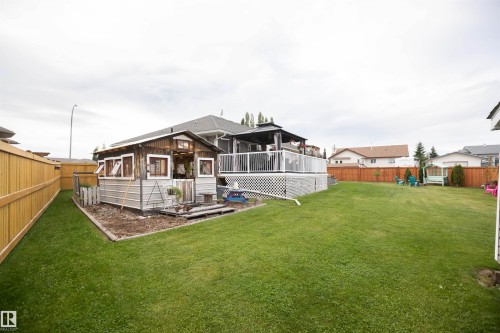 Expansive backyard featuring a manicured lawn, a raised wood deck with a gazebo, and a detached shed - 6003 50 Ave, Barrhead, AB 