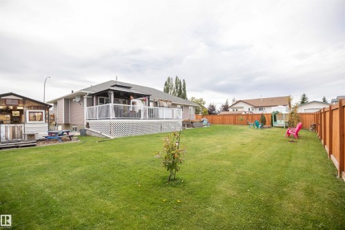 Expansive green lawn, raised rear deck with white railings, covered gazebo, and a privacy fence - 6003 50 Ave, Barrhead, AB 