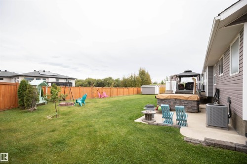 Expansive backyard with a full privacy fence, stone-look hot tub surround, and a covered gazebo - 6003 50 Ave, Barrhead, AB 