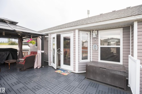 Spacious outdoor deck featuring modular tile flooring, a patio gazebo, and double French doors providing direct access to the interior - 6003 50 Ave, Barrhead, AB 