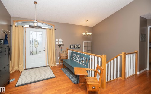 Front entry with wood-finish flooring, a decorative glass paneled door, and a transom window - 6003 50 Ave, Barrhead, AB 