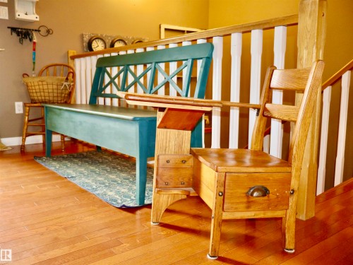 Wood-finish flooring with a wooden railing and white balusters - 6003 50 Ave, Barrhead, AB 