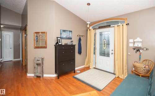 Entryway featuring a white door with decorative glass, an arched transom window, and wood-finish flooring - 6003 50 Ave, Barrhead, AB 