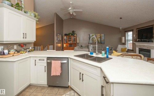 White cabinetry with dark hardware, stainless steel dishwasher, light-toned countertops, and a double basin sink with a high-arc faucet - 6003 50 Ave, Barrhead, AB 