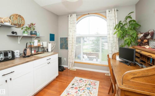 Wood-finish flooring with white baseboards, featuring a window with an arched transom - 6003 50 Ave, Barrhead, AB 