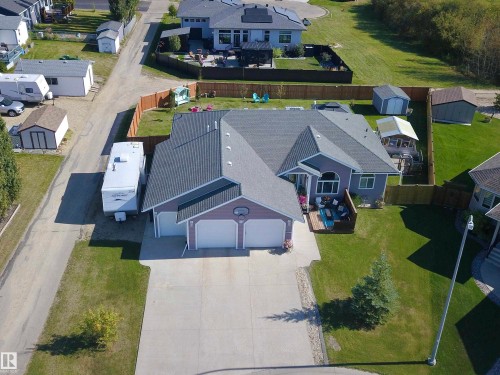 Spacious concrete driveway, attached two-car garage, expansive fenced backyard, composite deck, and shed - 6003 50 Ave, Barrhead, AB 