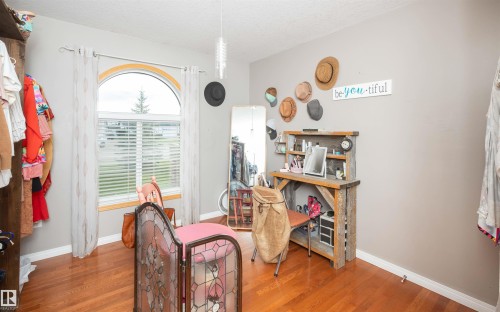 Hardwood flooring, arched window, neutral wall paint, built-in shelving, and recessed lighting - 6003 50 Ave, Barrhead, AB 