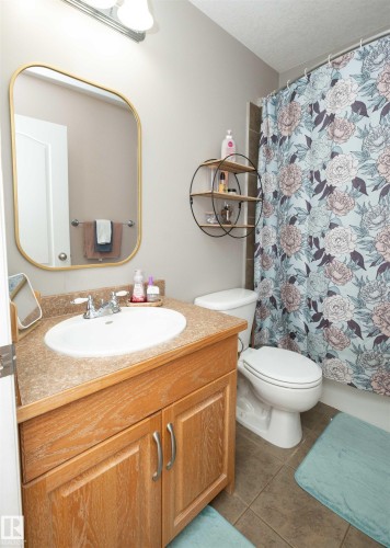 Spa-inspired bathroom featuring a wood-finish vanity with ample storage, round ceramic sink, and brushed brass hardware - 6003 50 Ave, Barrhead, AB 