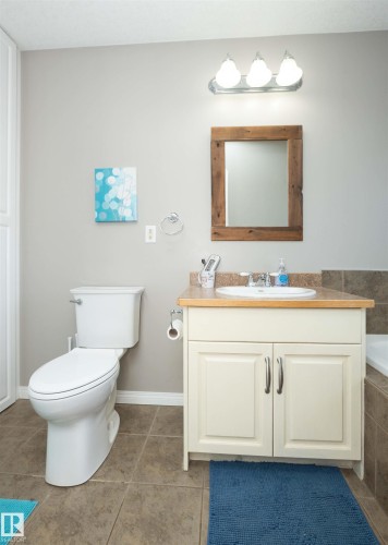 Bathroom featuring a vanity with an integrated sink, wood-finish countertop, and decorative mirror - 6003 50 Ave, Barrhead, AB 