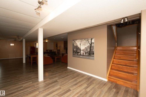 Expansive finished lower level featuring wood-finish flooring, a wood staircase, and track lighting - 6003 50 Ave, Barrhead, AB 