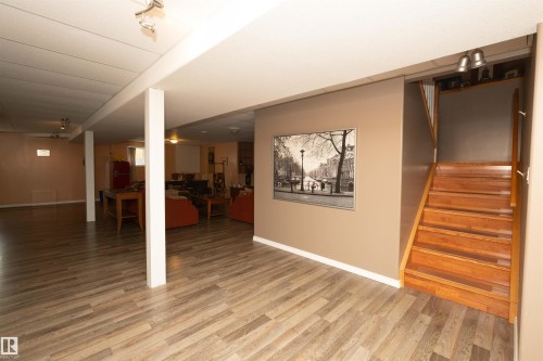 Wood-finish flooring, recessed lighting, and a solid wood staircase with a white railing - 6003 50 Ave, Barrhead, AB 