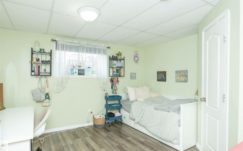 Recessed ceiling with acoustic tiles, wood-finish flooring, white trim, and a built-in closet with a paneled door - 6003 50 Ave, Barrhead, AB 