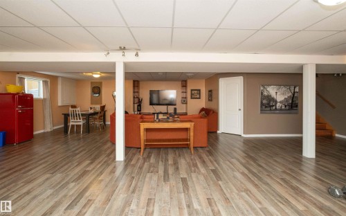 Expansive entertainment area featuring wood-finish flooring, recessed lighting, and a white drop ceiling - 6003 50 Ave, Barrhead, AB 