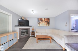 Corner fireplace with tile surround, dark wood-finish flooring, recessed ceiling lighting, and a large window with blinds - 