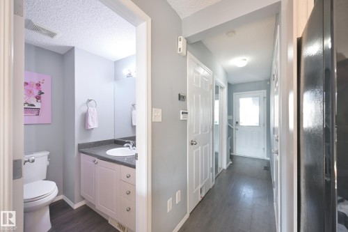 Powder room with a white toilet, single vanity with light-colored cabinetry, and dark countertop - 8127 7 Avenue Sw, Edmonton, AB 