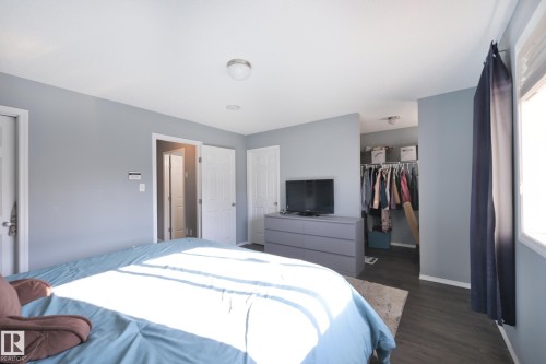 Spacious room with dark wood-finish flooring, light-colored walls, and a walk-in closet - 8127 7 Avenue Sw, Edmonton, AB 