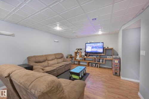 Recessed lighting illuminating the room, wood-finish flooring, light gray wall paint, and a decorative ceiling - 8127 7 Avenue Sw, Edmonton, AB 