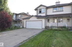Exterior featuring light-toned siding, attached garage, concrete driveway, and covered front entry - 