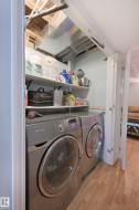 Laundry area featuring a front-loading washer and dryer, wood-finish flooring, and built-in shelving - 