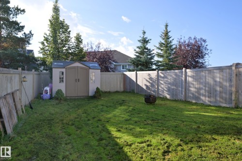 Expansive fenced yard featuring a storage shed, a fire pit, and mature perimeter trees - 8127 7 Avenue Sw, Edmonton, AB 