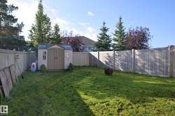 Expansive fenced yard featuring a storage shed, a fire pit, and mature perimeter trees - 