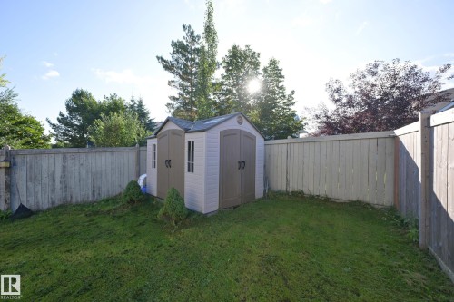 Fenced backyard featuring a storage shed with double doors and window details - 8127 7 Avenue Sw, Edmonton, AB 
