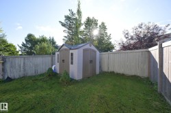 Fenced backyard featuring a storage shed with double doors and window details - 