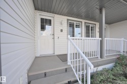 Covered entry featuring white siding and multiple pane windows - 