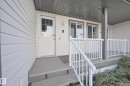 Covered entry featuring white siding and multiple pane windows - 8127 7 Avenue Sw, Edmonton, AB 