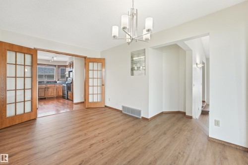 Open concept main living area featuring wood-finish flooring, a contemporary chandelier, and an illuminated recessed display niche - 8008 158 Avenue Nw, Edmonton, AB - Indoor Photo Showing Other Room