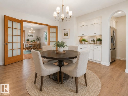 Dining area featuring wood-finish flooring, a brass chandelier, and built-in white cabinetry with a light-toned countertop - 8008 158 Avenue Nw, Edmonton, AB - Indoor Photo Showing Dining Room