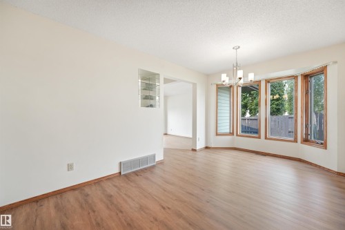 Open concept room featuring wood-finish flooring, a contemporary chandelier, and a built-in wall display cabinet - 8008 158 Avenue Nw, Edmonton, AB - Indoor Photo Showing Other Room