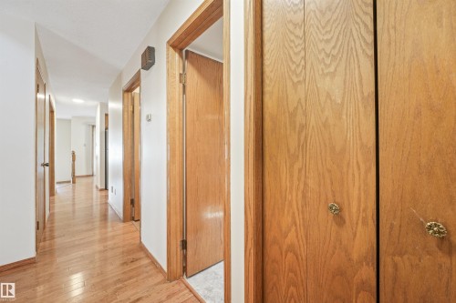 Hallway featuring wood-finish flooring, white walls, and wood doors with decorative hardware - 8008 158 Avenue Nw, Edmonton, AB - Indoor Photo Showing Other Room