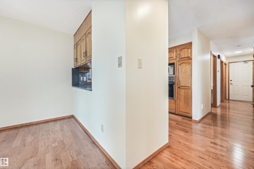 Hardwood-finish flooring extending into the hallway - 8008 158 Avenue Nw, Edmonton, AB - Indoor Photo Showing Other Room