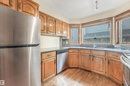 Kitchen featuring oak cabinetry, a stainless steel refrigerator, and a stainless steel dishwasher - 8008 158 Avenue Nw, Edmonton, AB - Indoor Photo Showing Kitchen With Stainless Steel Kitchen