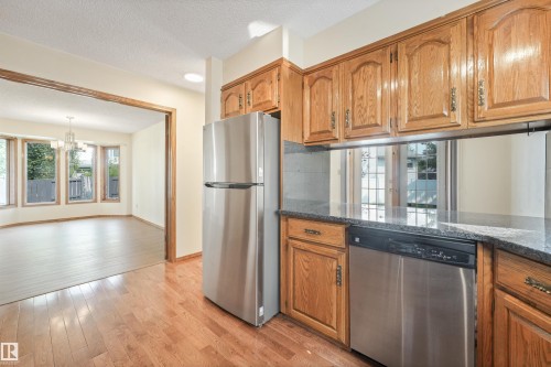Kitchen featuring wood cabinetry, stainless steel appliances, and granite-style countertops - 8008 158 Avenue Nw, Edmonton, AB - Indoor Photo Showing Kitchen
