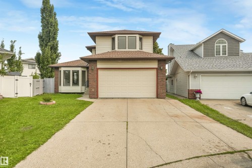 Two-story residence featuring a two-car garage with an overhead door, a brick facade accent, and light-colored siding - 8008 158 Avenue Nw, Edmonton, AB - Outdoor With Facade