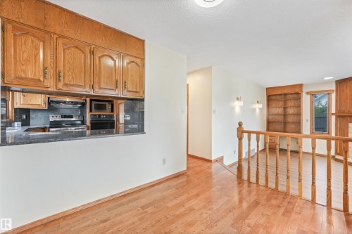 Kitchen pass-through with wood cabinetry and black countertop - 8008 158 Avenue Nw, Edmonton, AB - Indoor Photo Showing Kitchen