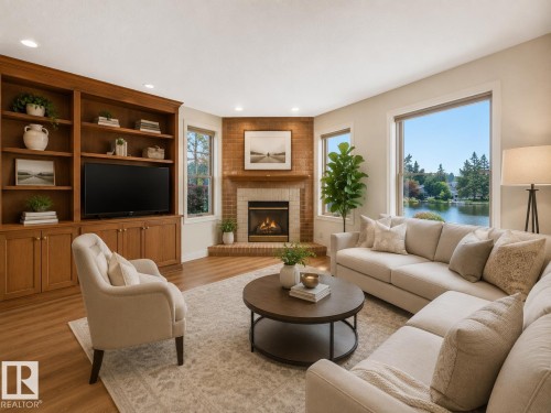 Living area featuring large windows with a prominent water backdrop, a corner brick fireplace with a mantle, and a built-in entertainment center with shelving and storage - 8008 158 Avenue Nw, Edmonton, AB - Indoor Photo Showing Living Room With Fireplace
