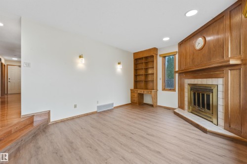 Corner fireplace with wood-finish surround and hearth, featuring a tile accent - 8008 158 Avenue Nw, Edmonton, AB - Indoor With Fireplace