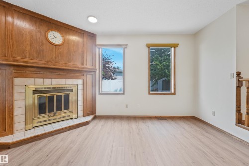 Corner fireplace with wood paneling and tile surround - 8008 158 Avenue Nw, Edmonton, AB - Indoor Photo Showing Living Room With Fireplace