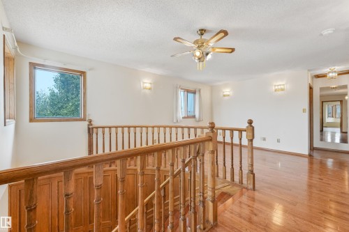 Spacious upper-level landing featuring wood flooring and a matching wood staircase with railing - 8008 158 Avenue Nw, Edmonton, AB - Indoor Photo Showing Other Room