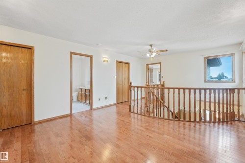 Upper level featuring wood-finish flooring, a wood banister, and a ceiling fan - 8008 158 Avenue Nw, Edmonton, AB - Indoor Photo Showing Other Room