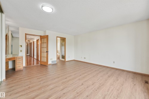 Spacious room featuring wood-finish flooring, light-toned walls, and a ceiling-mounted light fixture - 8008 158 Avenue Nw, Edmonton, AB - Indoor Photo Showing Other Room