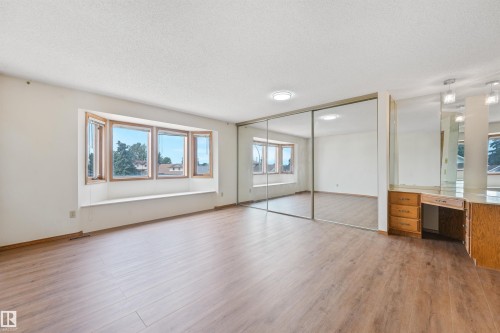 Spacious room featuring wood-finish flooring and a multi-pane bay window with a built-in window seat - 8008 158 Avenue Nw, Edmonton, AB - Indoor Photo Showing Other Room