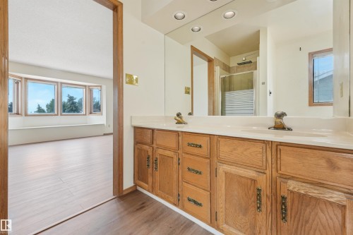 Double vanity with integrated sinks, wood-finish cabinetry, and a full-width mirror - 8008 158 Avenue Nw, Edmonton, AB - Indoor Photo Showing Bathroom