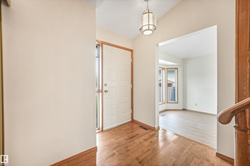Entryway featuring wood-finish flooring, a white paneled door with sidelight, and a decorative pendant light - 8008 158 Avenue Nw, Edmonton, AB - Indoor Photo Showing Other Room