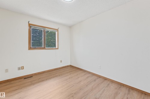 Bright room featuring a wood-framed window, neutral wall paint, wood-finish flooring, and a ceiling-mounted light fixture - 8008 158 Avenue Nw, Edmonton, AB - Indoor Photo Showing Other Room