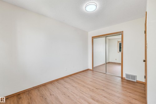 Spacious room featuring wood-finish flooring, white walls, and a ceiling-mounted light fixture - 8008 158 Avenue Nw, Edmonton, AB - Indoor Photo Showing Other Room